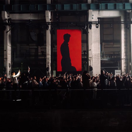 A red banner with F1 driver Gabriel Bortoleto shown in silhouette, at the Audi Revolut F1 Team launch event in Berlin