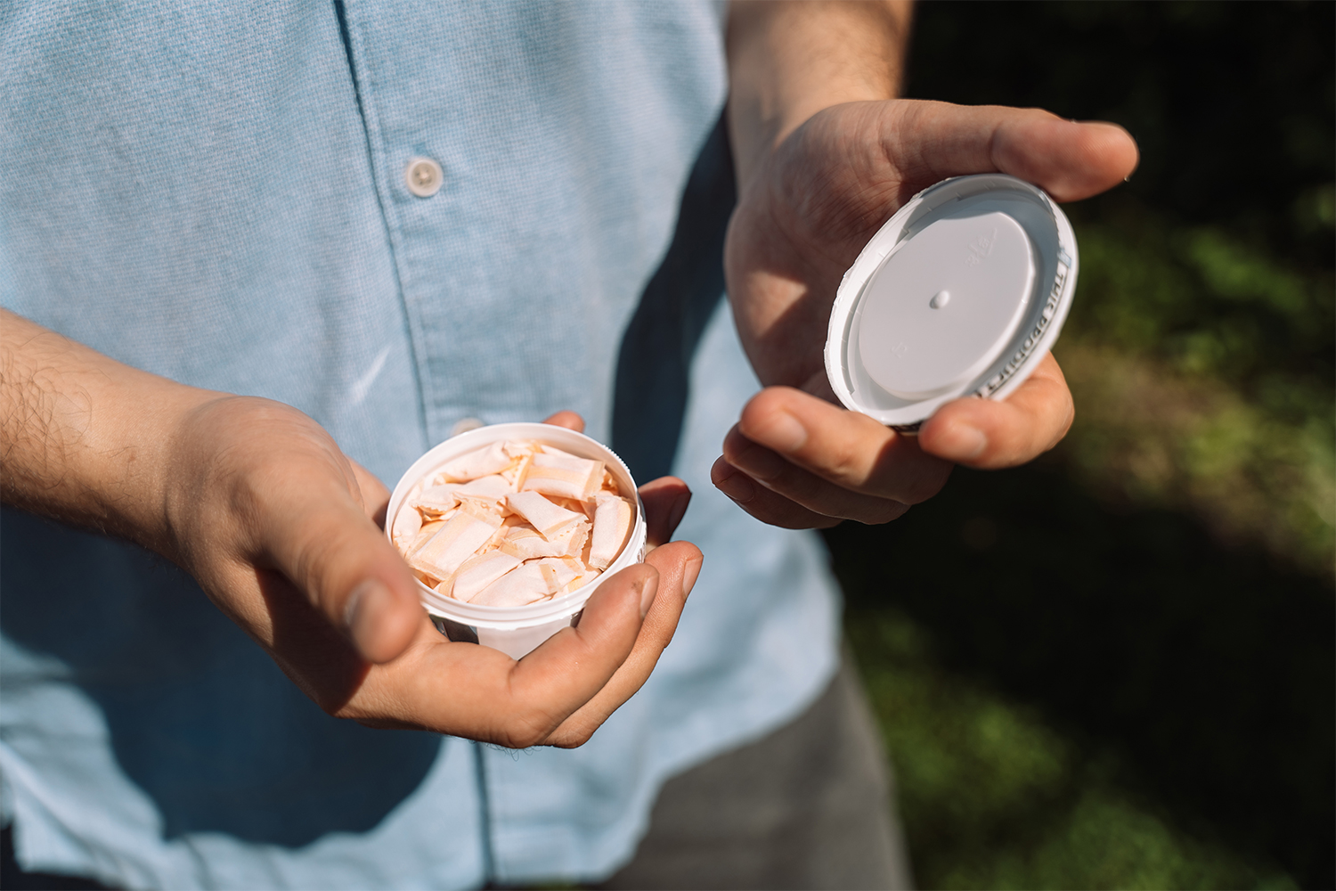 A man opening a container of nicotine pouches, or snus. The stimulant is gaining ground among wellness influencers.