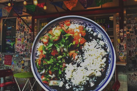 a bowl of rice and beans with cheese and pico de gallo overlaid on a photo of SoHo restaurant La Esquina