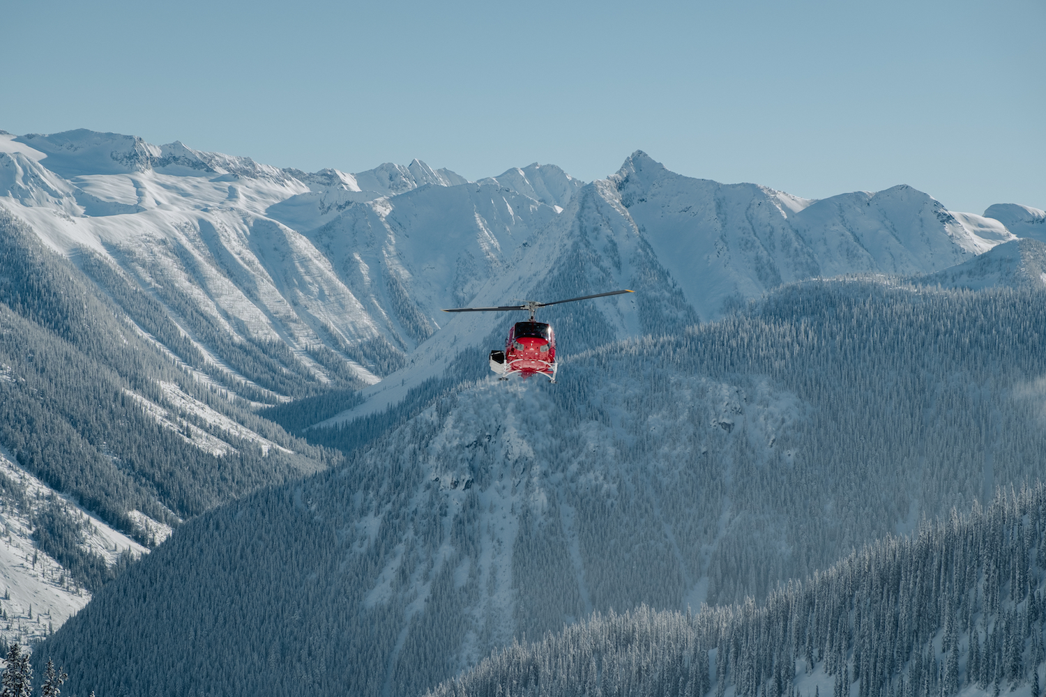 A red helicopter against the snowy mountain peaks.