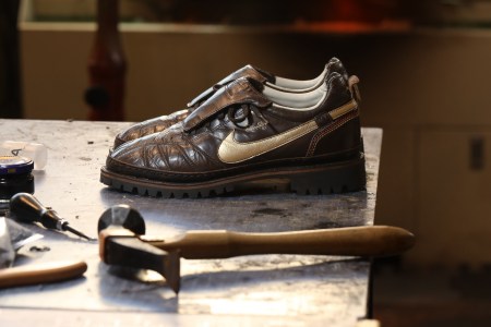 A pair of brown shoes on a table with a hammer in the foreground