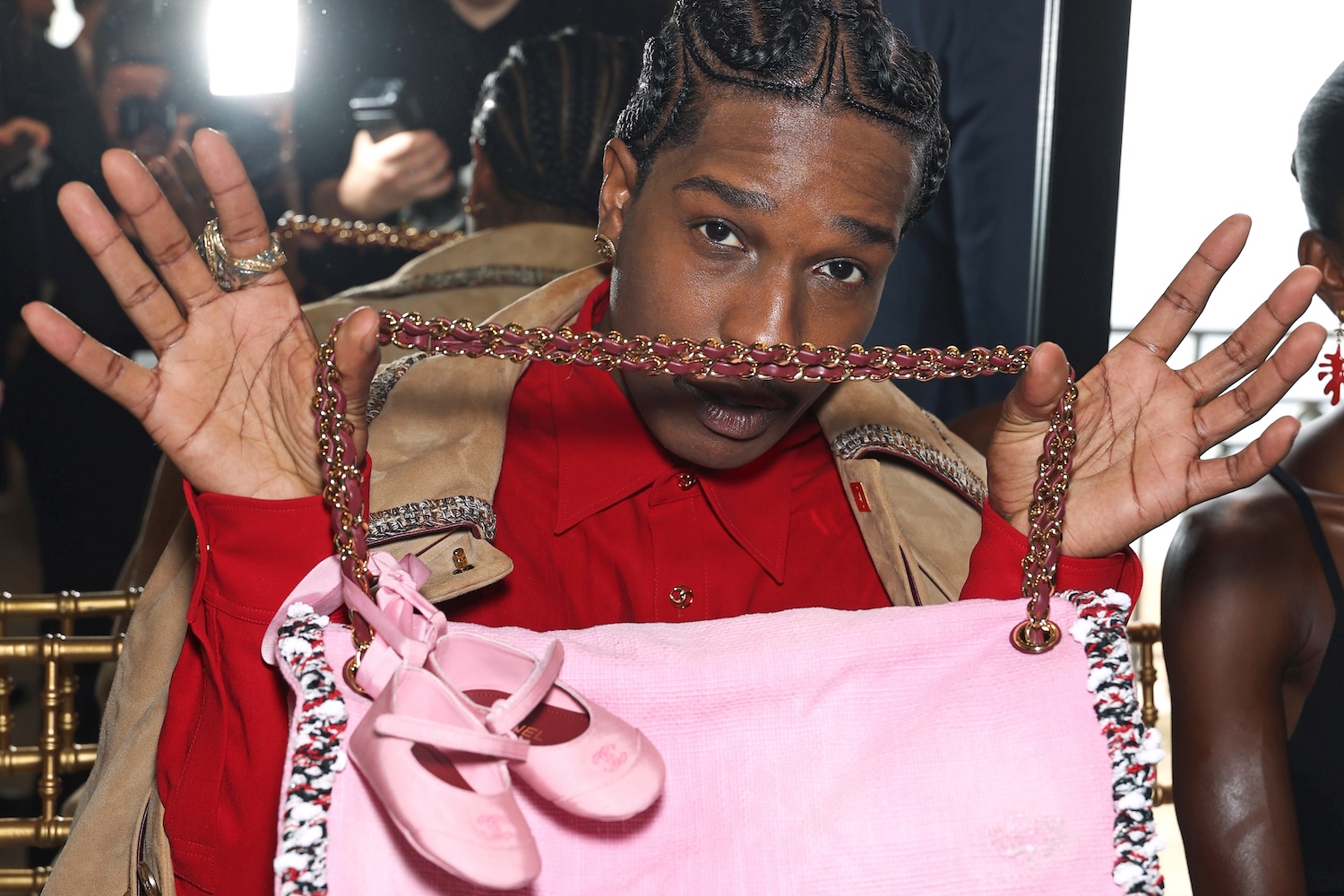 A man holding up a pink bag with baby ballet flats attached to the handle