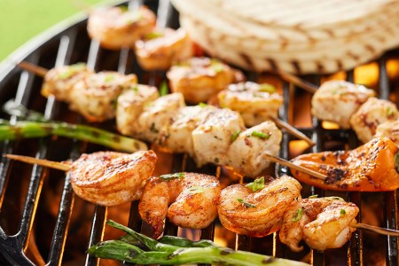 Shrimp and chicken skewers and vegetables on a grill