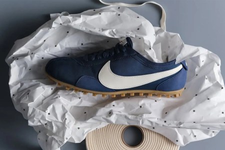 A blue shoe with a white Nike swoosh logo sitting on a piece of crumpled paper