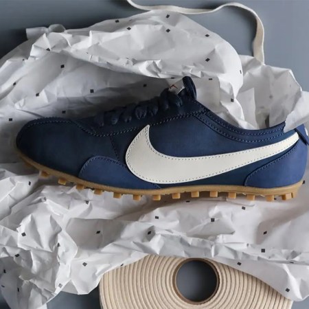 A blue shoe with a white Nike swoosh logo sitting on a piece of crumpled paper