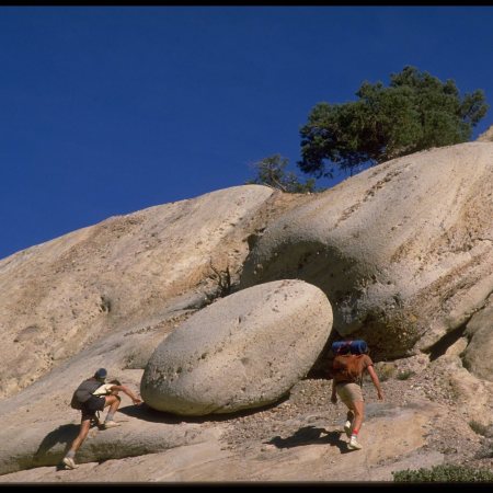 Two men scrambling up rocks.