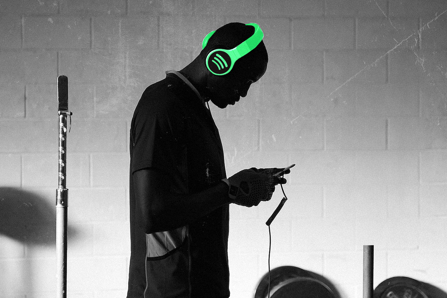A man looking at a phone, wearing headphones with a lime-green Spotify illustration.