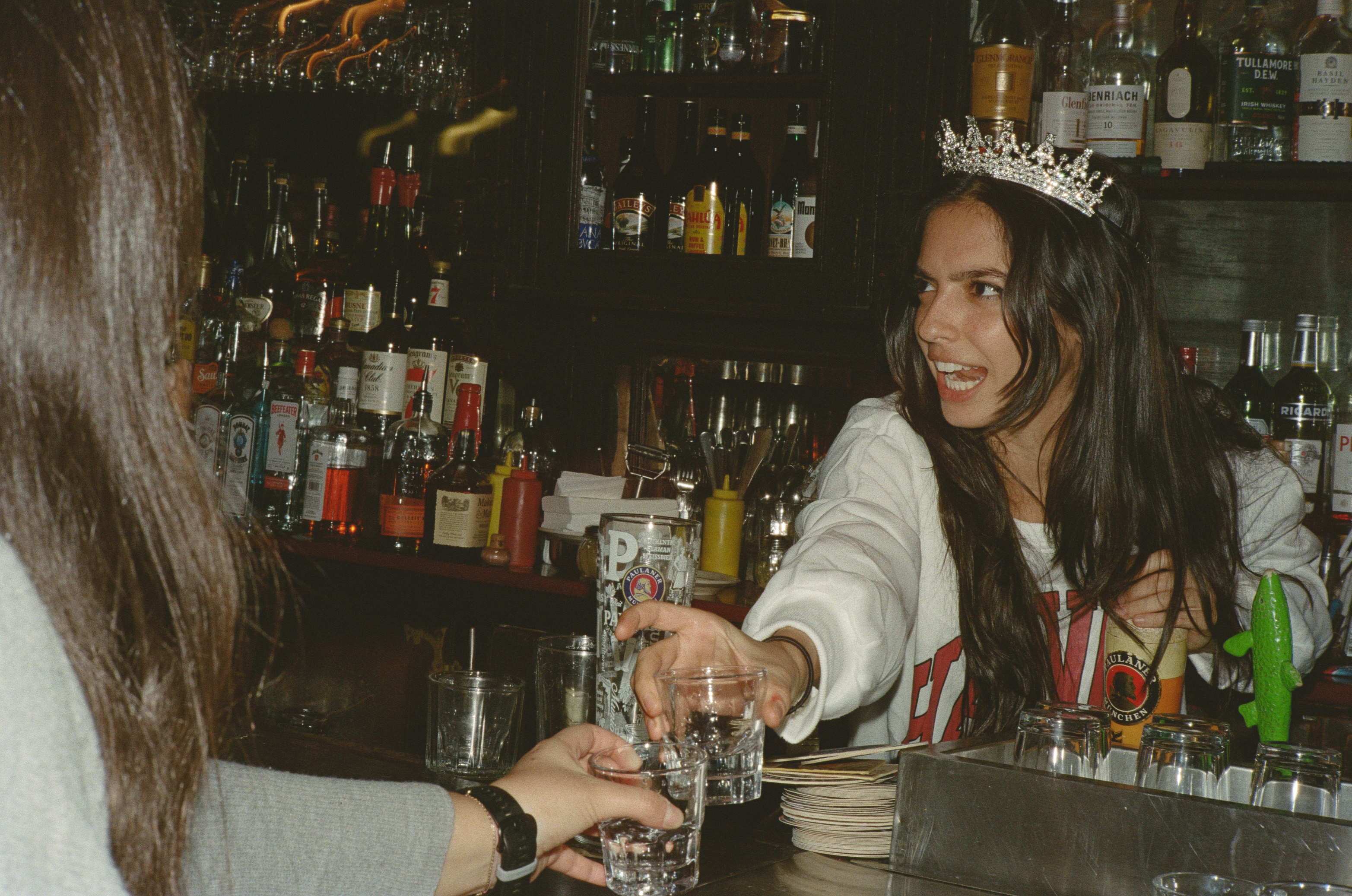 A woman standing behind the bar serving shots