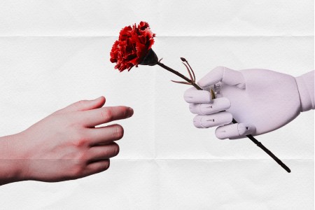 A human hand extending to reach for a rose being given by a robot hand