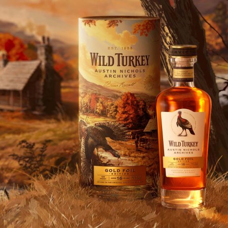 A bottle of whiskey sitting next to a cylindrical container with a barn illustration in the background