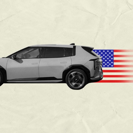 A gray and black car driving to the left with an American flag trailing behind it fading into a beige background