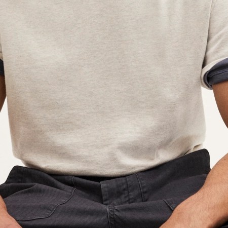 Torso of a person wearing a light gray t-shirt with rolled-up dark gray sleeves and dark gray pants.