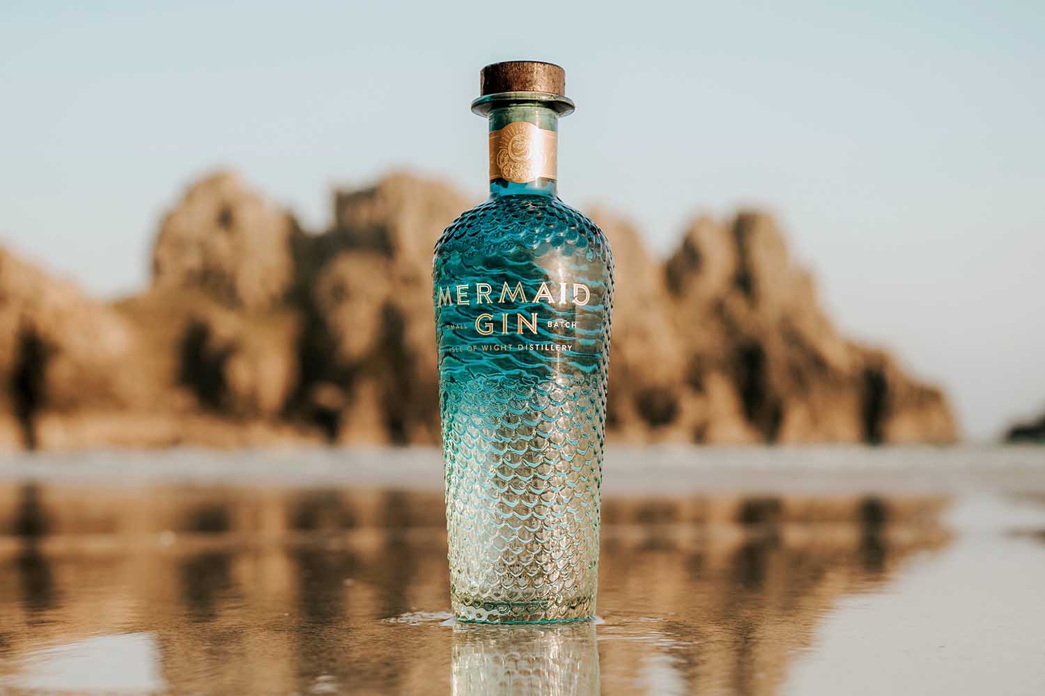 Mermaid Gin bottle on the beach near the ocean water
