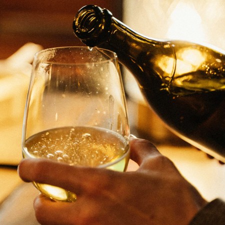 a man holding a goblet and pouring sparkling wine into it