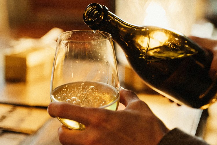 a man holding a goblet and pouring sparkling wine into it