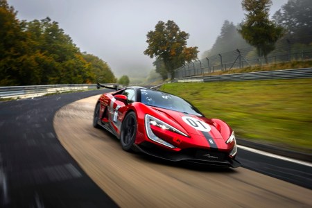 A red and black car driving fast around a racetrack