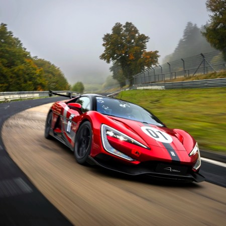 A red and black car driving fast around a racetrack