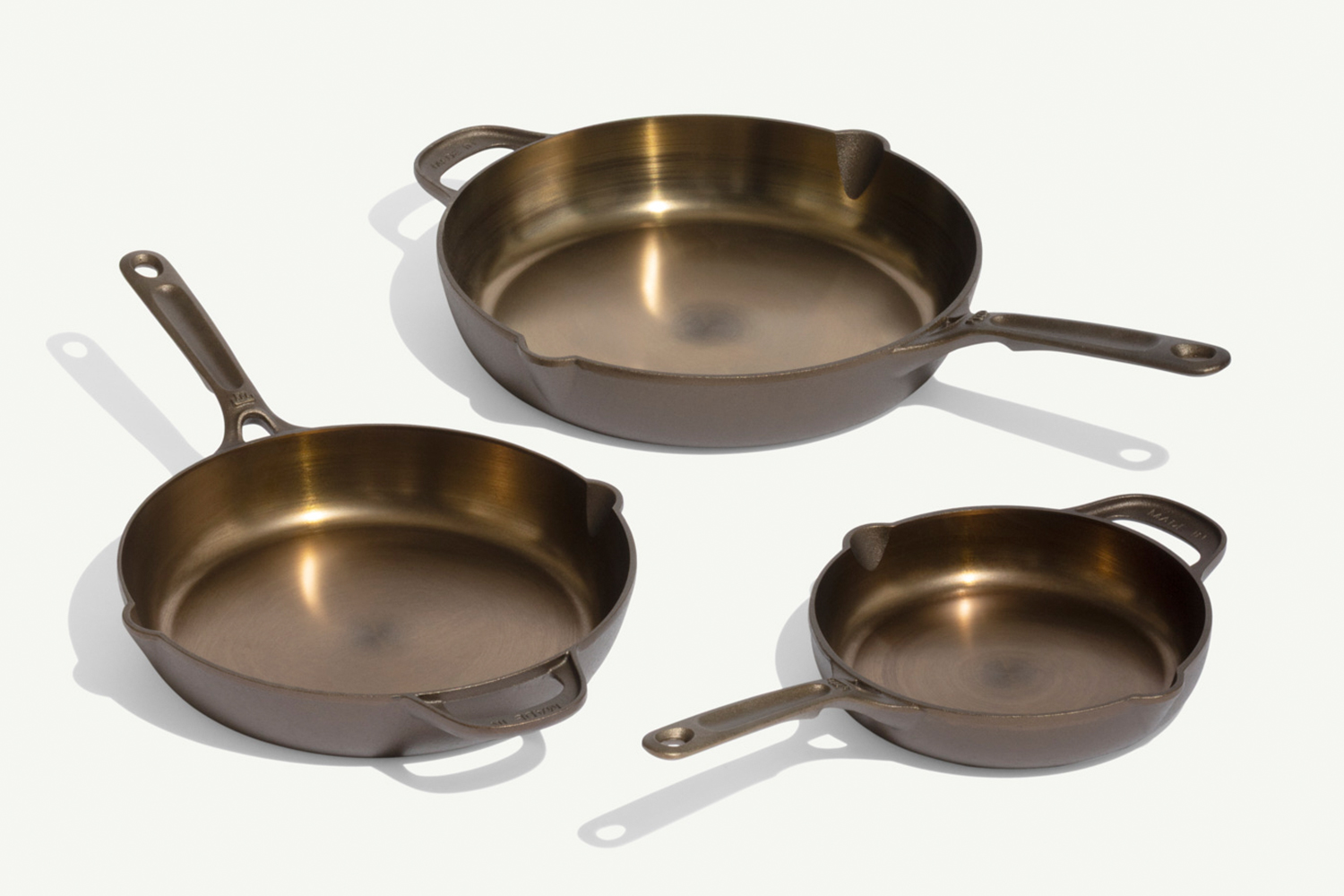 Three cast iron skillets of different sizes arranged on a white background