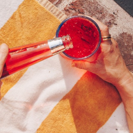 A red drink being poured from a Phony Negroni bottle
