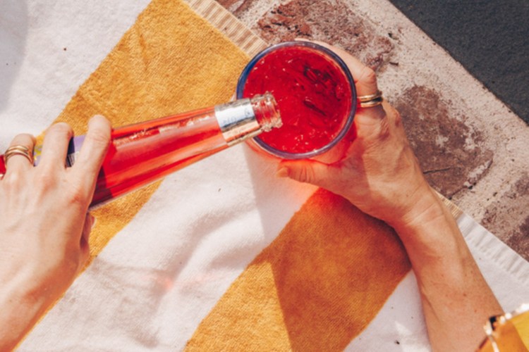 A red drink being poured from a Phony Negroni bottle