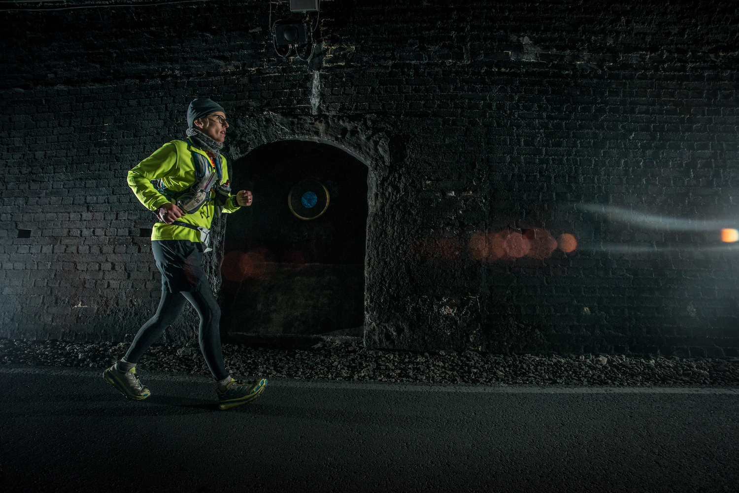 A woman running down a dark tunnel.