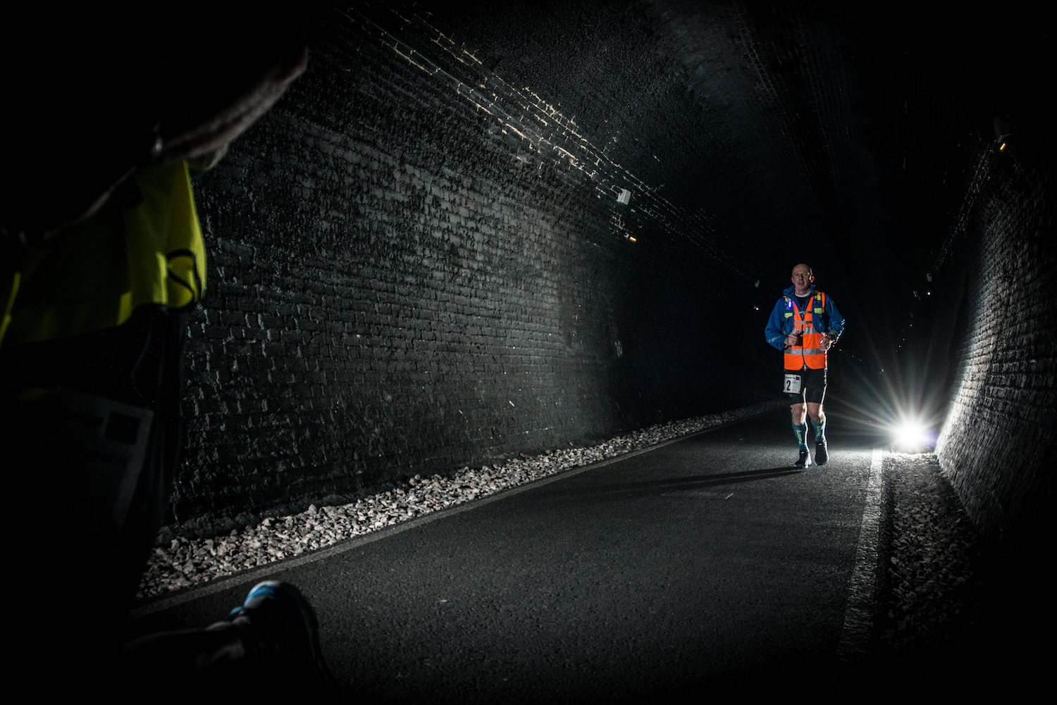 Runners in a dark, narrow tunnel.