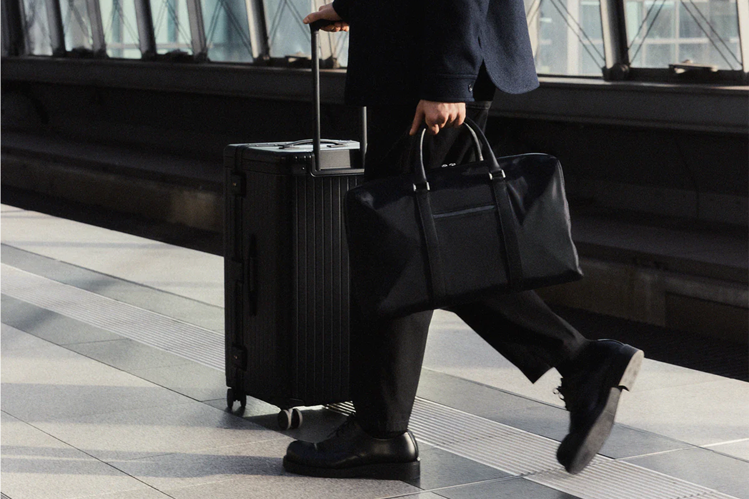 Carl Friedrik lifestyle image of man holding weekender bag pushing suitcase