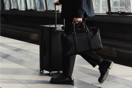Carl Friedrik lifestyle image of man holding weekender bag pushing suitcase