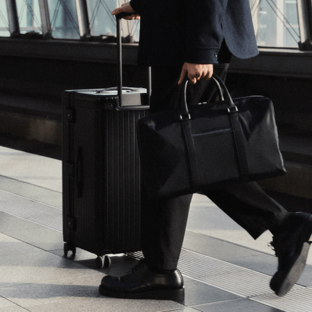 Carl Friedrik lifestyle image of man holding weekender bag pushing suitcase