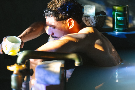 A man sitting in a bath holding a cup of coffee
