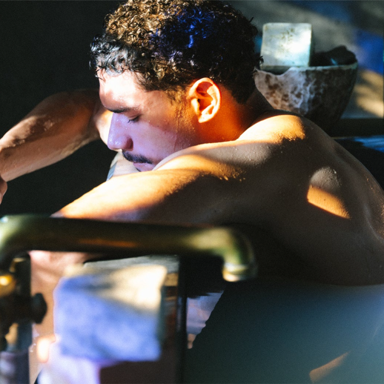 A man sitting in a bath holding a cup of coffee