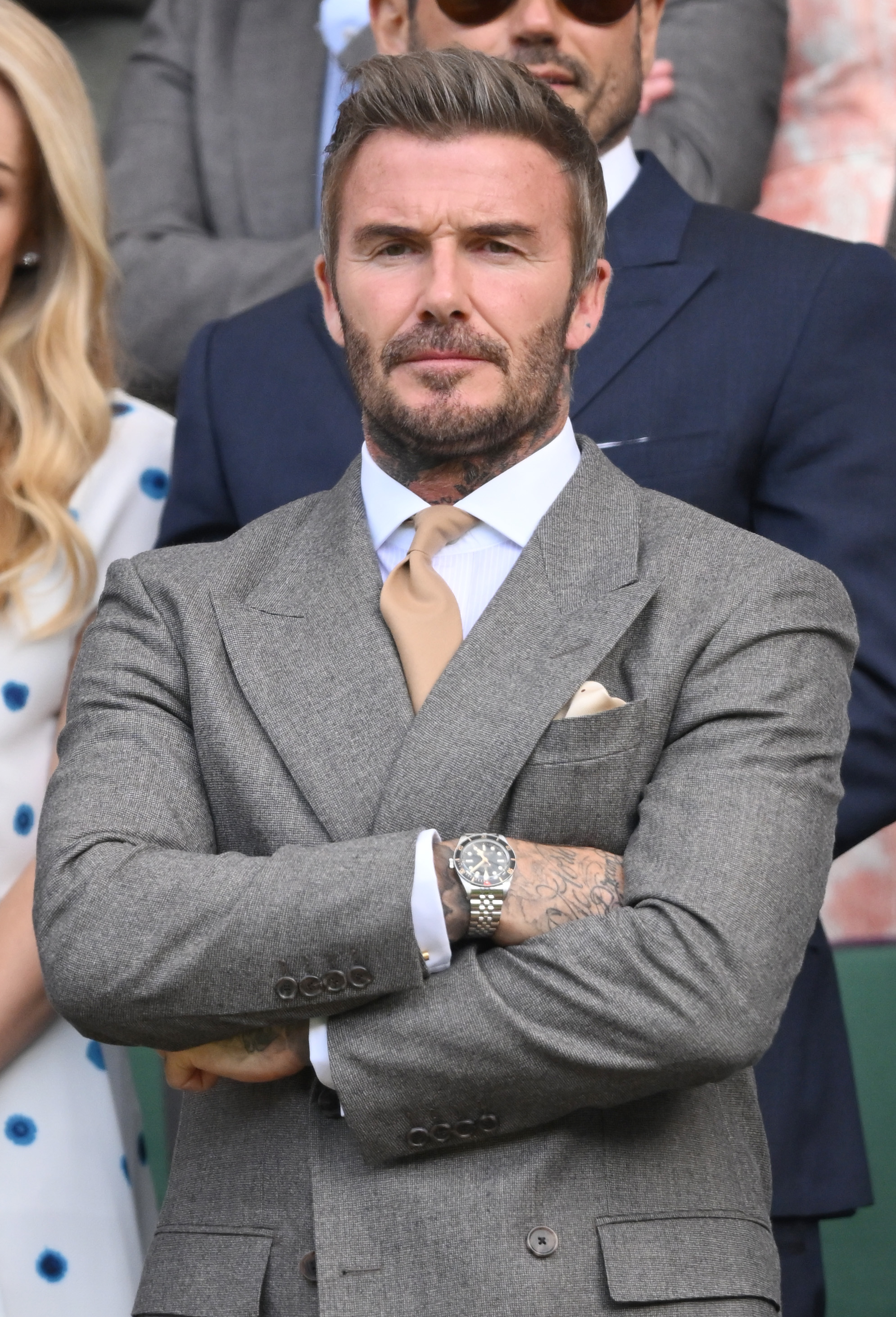 David Beckham watching a tennis match in a grey suit