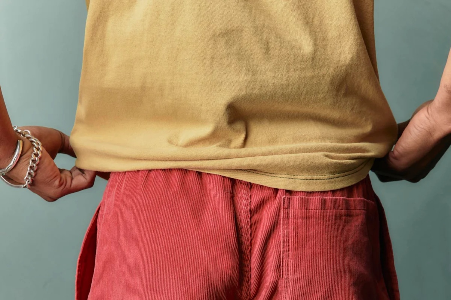A model wearing a yellow shirt and red cord shorts.