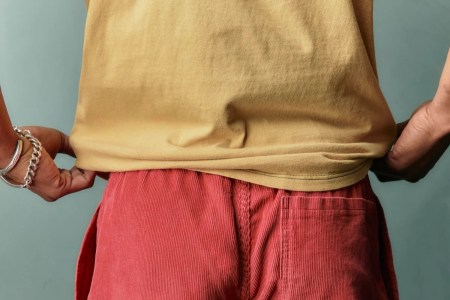 A model wearing a yellow shirt and red cord shorts.
