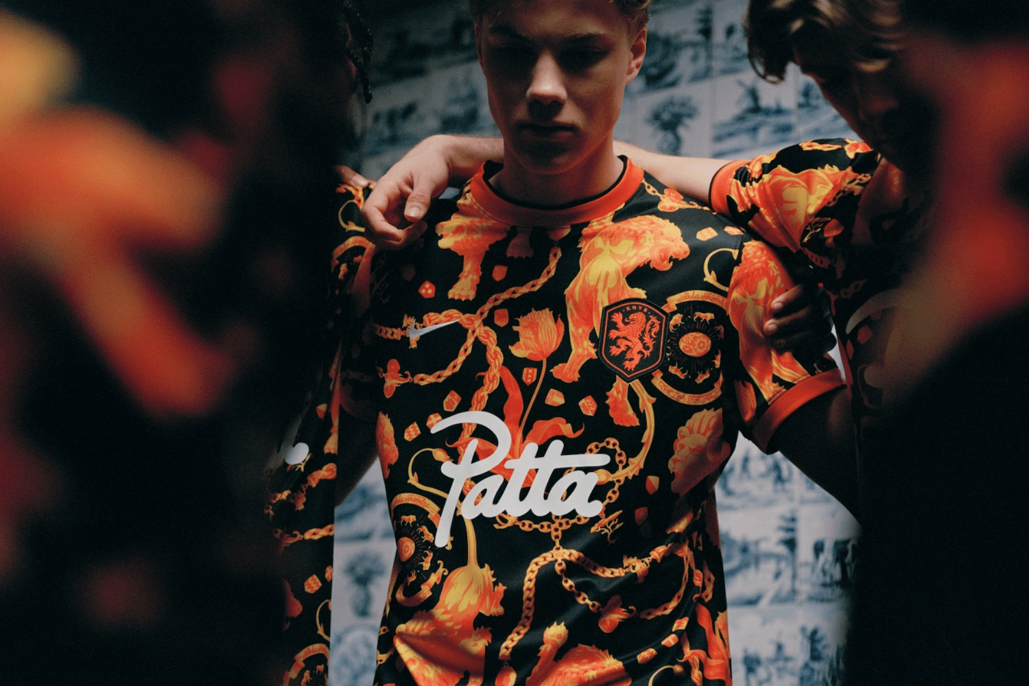 a model wearing an orange Patta x Netherlands kit