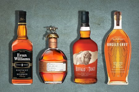 bottles of evan williams, blanton's buffalo trace and angels envy bourbons on a gray background