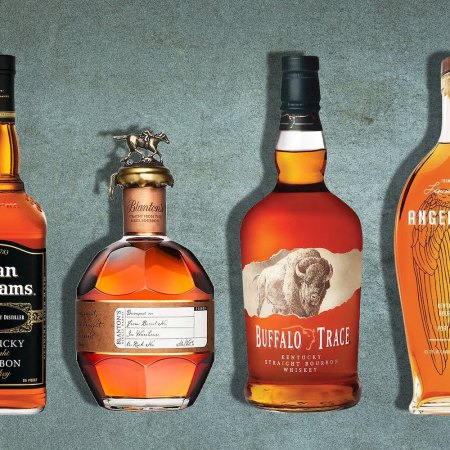 bottles of evan williams, blanton's buffalo trace and angels envy bourbons on a gray background