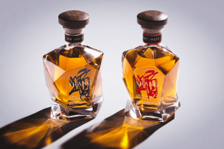 Two bottles of Shang whiskey on a grey background, with shadows