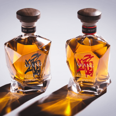 Two bottles of Shang whiskey on a grey background, with shadows