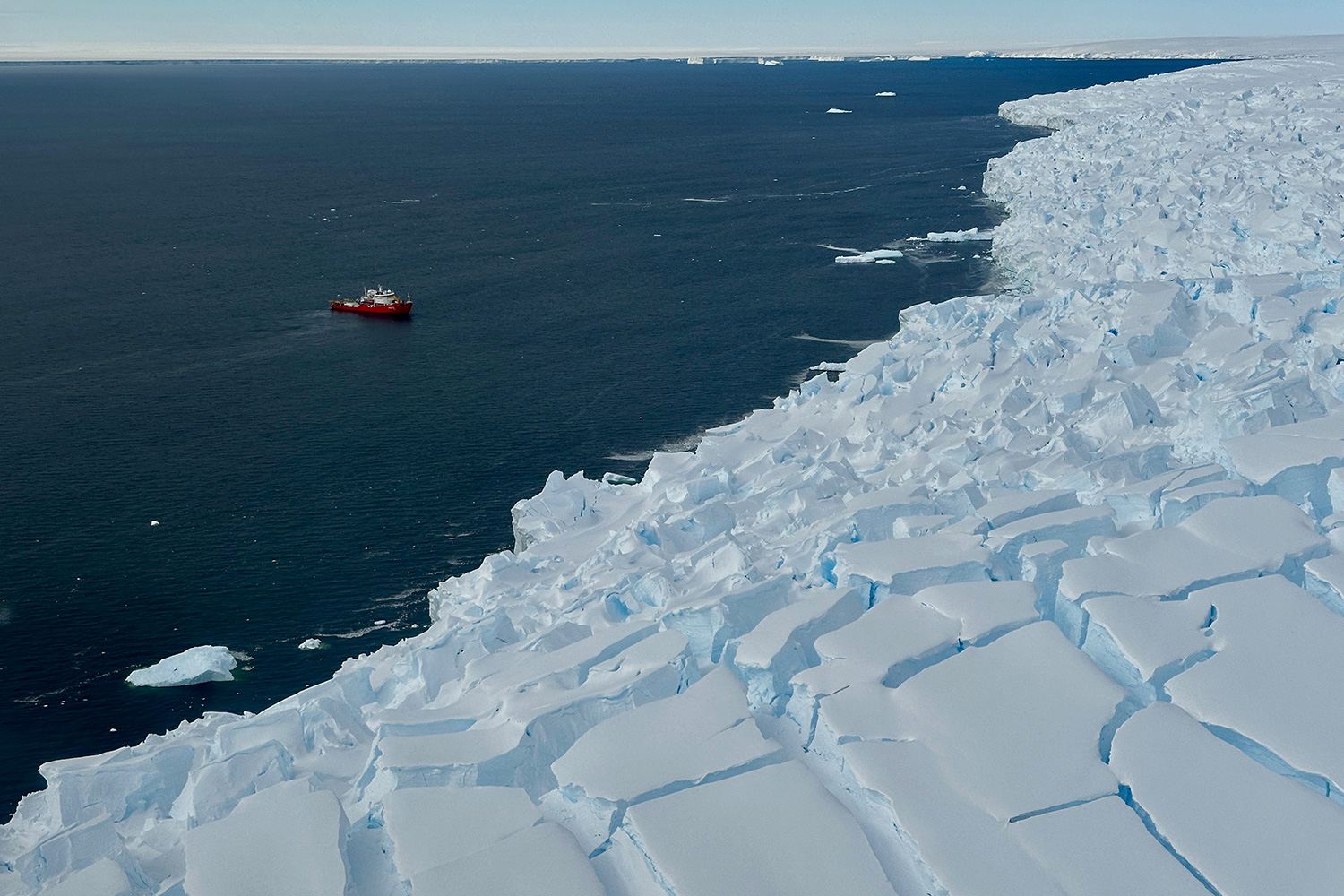 A red and white icebreaker floating in the ocean off the coast of Antarctica