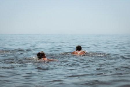 A pair of swimmers in the open ocean swimming toward the horizon