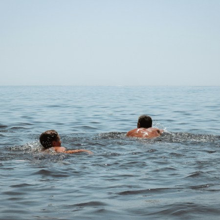 A pair of swimmers in the open ocean swimming toward the horizon