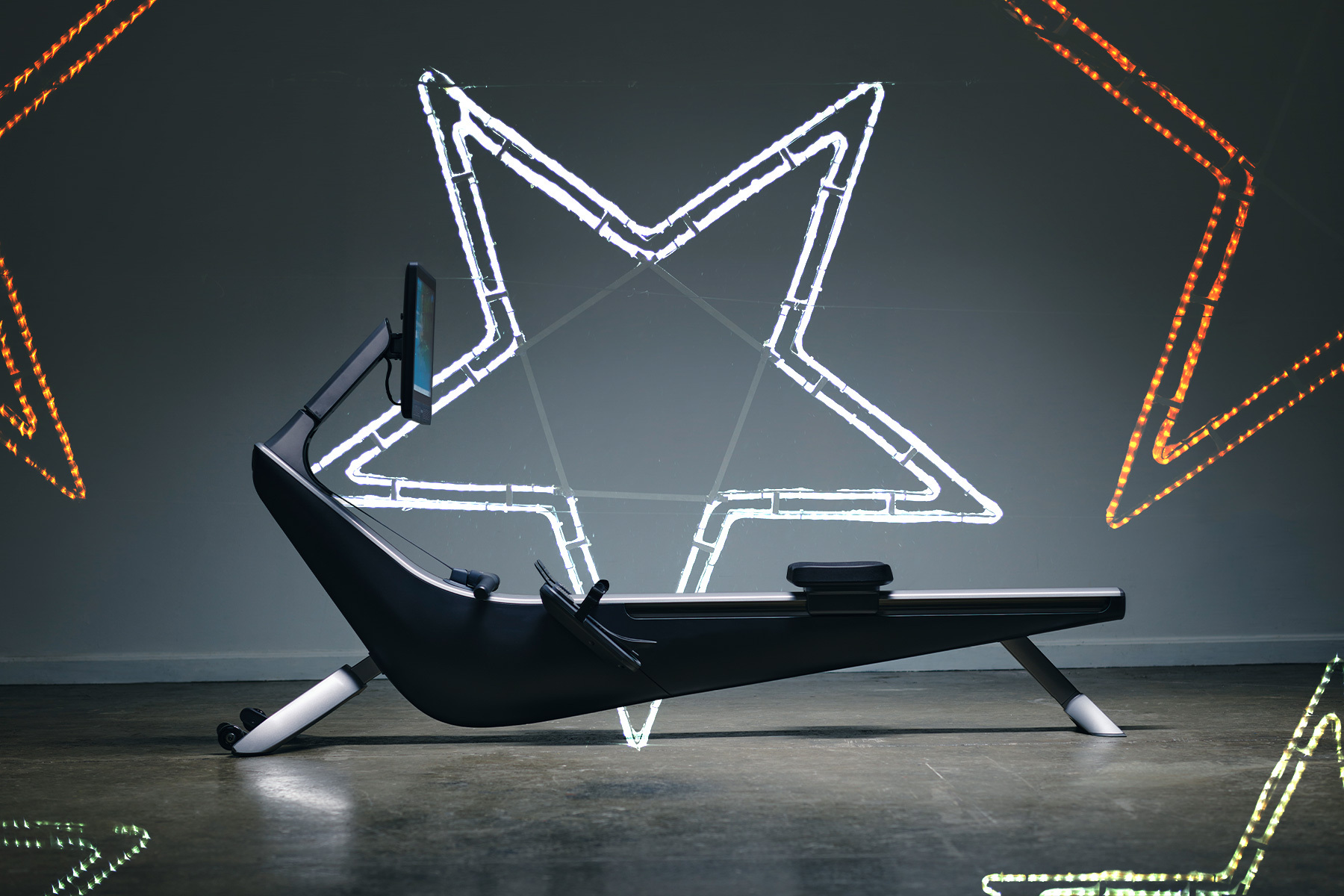 A rowing machine flanked by neon lights in the shape of stars