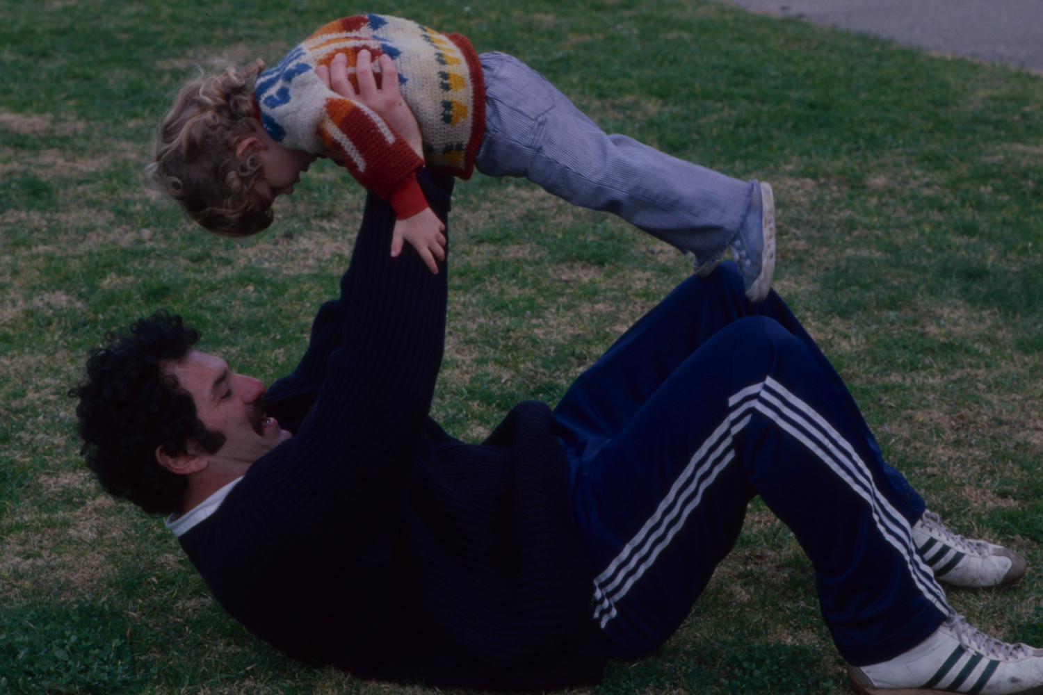 A man on his back, holding his son up.