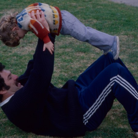 A man on his back, holding his son up.