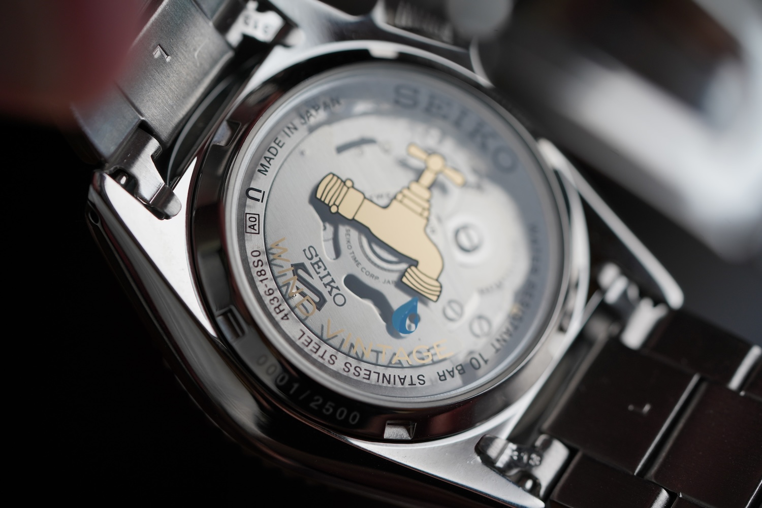 A stainless steel watch caseback with a pipe graphic