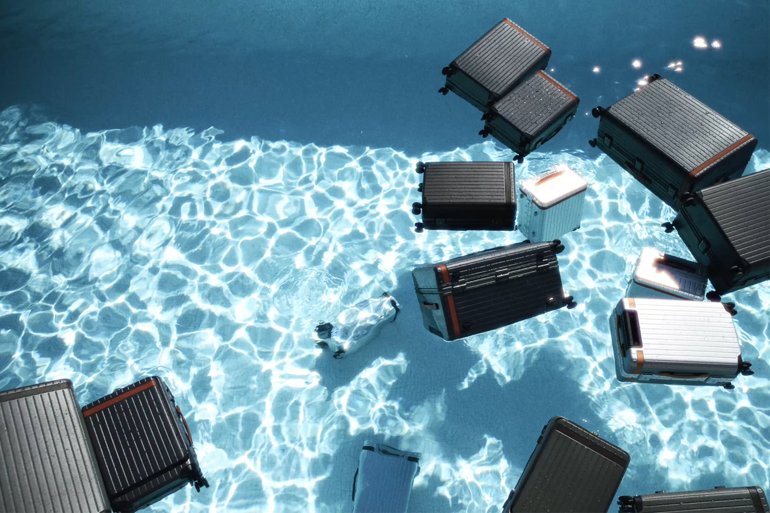 Various pieces of Carl Friedrik luggage floating in a pool