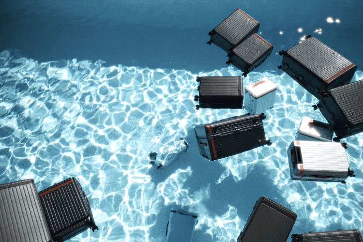 Various pieces of Carl Friedrik luggage floating in a pool