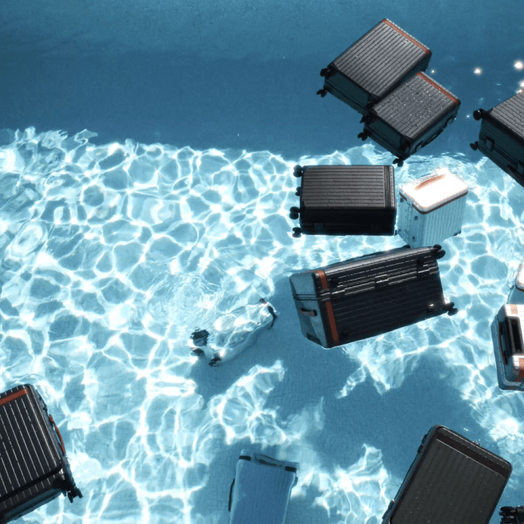 Various pieces of Carl Friedrik luggage floating in a pool