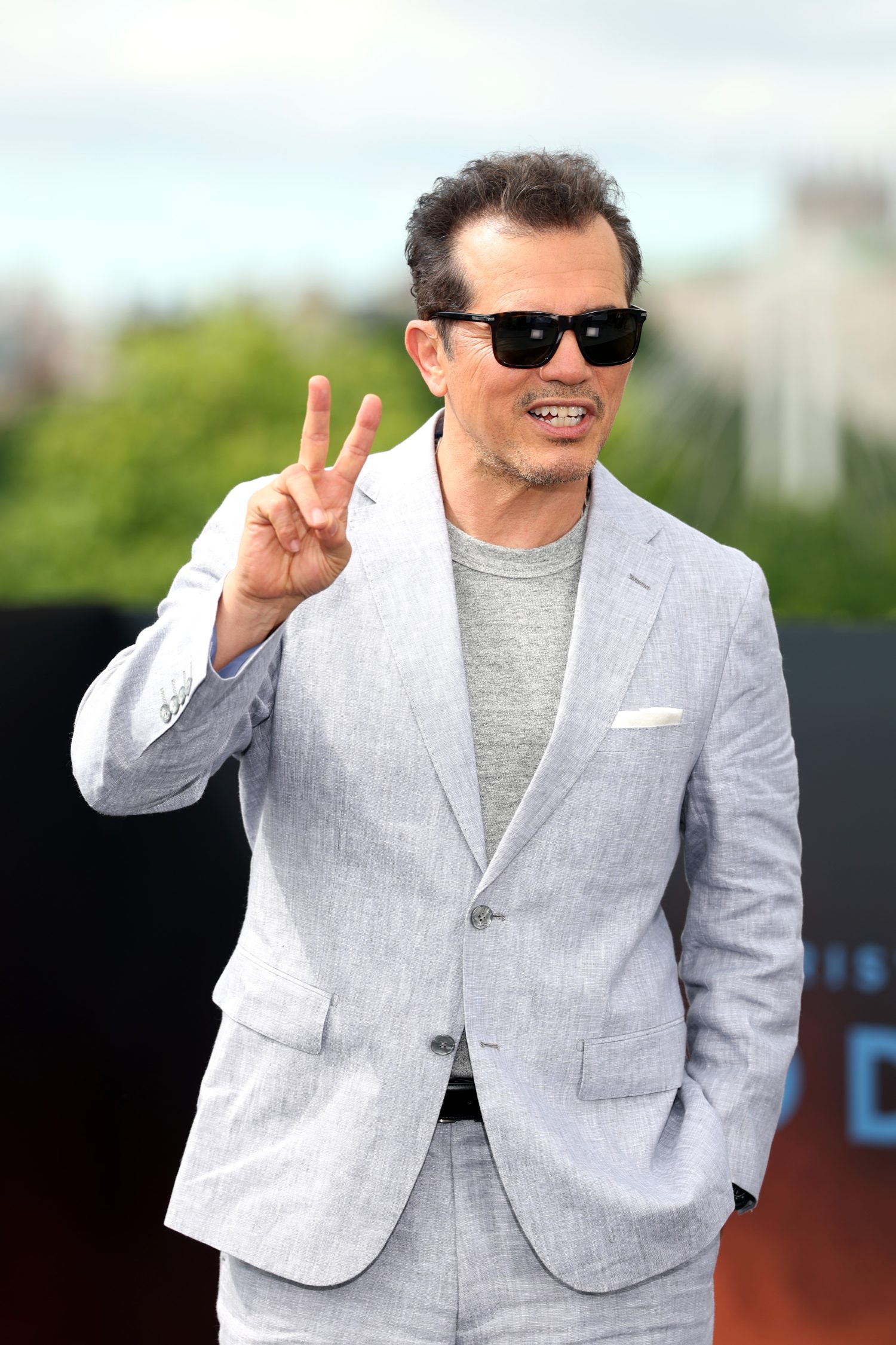 A man in a light seersucker suit and sunglasses standing for a photo.